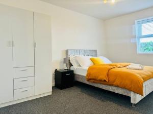 倫敦的住宿－Unique 2 bedroom Flat 15 mins via tube to Central London，白色卧室配有带橙色毯子的床