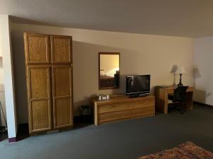 een kamer met een televisie en een bureau met een spiegel bij Country Haven Inn in Burlington