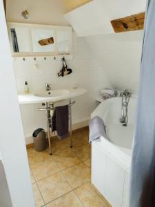 W łazience znajduje się biała wanna i umywalka. w obiekcie Epicerie Gourmande w mieście Villandry