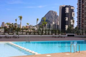 een zwembad met stoelen en een berg op de achtergrond bij Apartamento de lujo Alexia 1 Calpe in Calpe