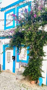 a blue and white building with a tree and flowers at Zenit charm Olhao relax cubist House in Olhão