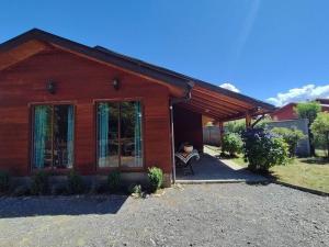 een rood huis met een veranda met een bankje erbuiten bij Refugio en la ciudad in Pucón