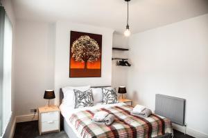 a bedroom with a bed with a tree painting on the wall at MantonHouse by Sheryl - Sleeps 7 in Liverpool