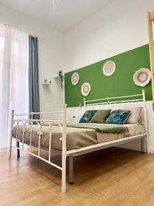 un letto bianco in una stanza con parete verde di San marco 56 a Bari