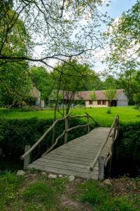 eine Holzbrücke über ein Feld mit einem Haus in der Unterkunft Domaine Moulin de Boiscorde in Rémalard