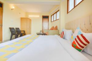 ein Schlafzimmer mit einem großen weißen Bett mit bunten Kissen in der Unterkunft OYO Home 78009 Avon Villa Kanlog in Shimla