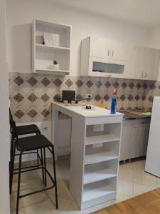 een witte keuken met een aanrecht en een kruk bij Marko apartman in Surčin