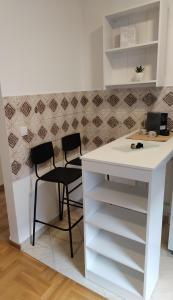 een keuken met een wit aanrecht en 2 stoelen bij Marko apartman in Surčin