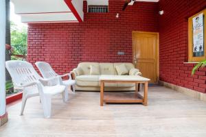 a living room with a couch and two white chairs at OYO Home Gautam Homestay in Dehradun
