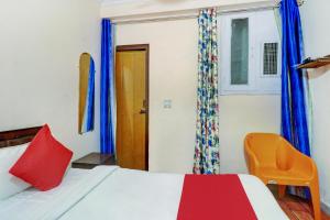 a bedroom with a bed and a orange chair at Ratiram Hotel Near Worlds of Wonder in Kalkaji Devi