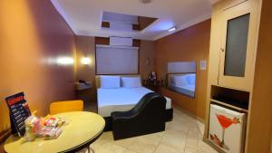 um pequeno quarto de hotel com uma cama e uma mesa em Swing Motel 1 em São Paulo