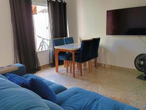 a living room with a table and a blue couch at Triplex 3 quartos a 100 metros de Costa Azul in Rio das Ostras