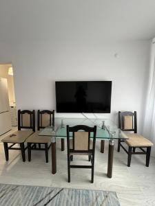 sala de estar con mesa, sillas y TV de pantalla plana. en Apartament Central en Râmnicu Vâlcea