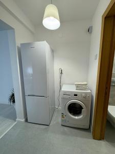 a white refrigerator and a washing machine in a room at Apartament Central in Râmnicu Vâlcea
