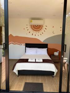 um quarto com uma cama e uma parede com um sol em VerdeSelva em Doradal