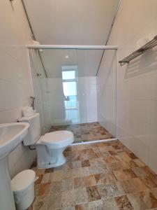 グアルジャにあるSuítes Pitangueirasのバスルーム(トイレ、ガラス張りのシャワー付)
