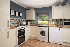 a kitchen with white cabinets and a washer and dryer at Wood Cottage in Coldstream