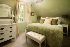 a bedroom with a bed with a green comforter at Wood Cottage in Coldstream