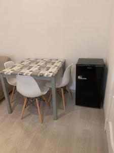 a table with white chairs and a black refrigerator at AngelHome Matera in Matera