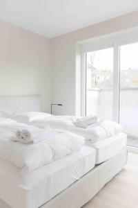 a row of white beds in a white bedroom at Bootsmann in Sankt Peter-Ording