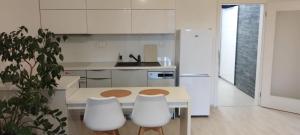 a white kitchen with a table and white chairs at Apartments Modřanka in Prague