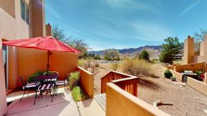 a patio with a table and chairs and a red umbrella at River Days #3326 in Moab