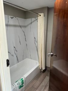 a bathroom with a white tub and a shower curtain at Nola Inn & Suites in New Orleans