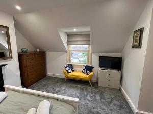 a bedroom with a yellow couch and a television at The Loft at Scalford House in Melton Mowbray