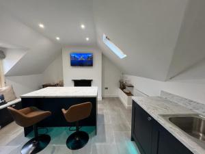 a kitchen with a sink and a counter with two chairs at The Loft at Scalford House in Melton Mowbray