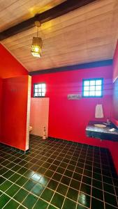 ein Bad mit einer roten Wand und einem Waschbecken in der Unterkunft Chácara Cajueiro in Araras