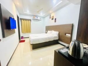 um pequeno quarto com uma cama e uma televisão em Deccan Suites, Tirupati em Tirupati