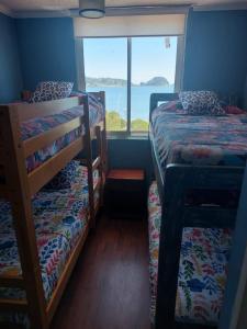 a bedroom with two bunk beds and a large window at Dichato Borde Bahía Azul in Tomé