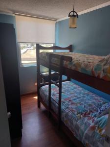 1 dormitorio con 2 literas y ventana en Dichato Borde Bahía Azul, en Tomé