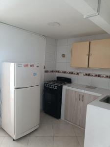 a kitchen with a stove and a white refrigerator at San antonio urbano in Bogotá