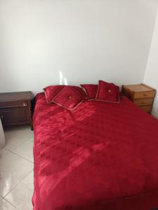 uma cama vermelha com lençóis e almofadas vermelhas num quarto em San antonio urbano em Bogotá