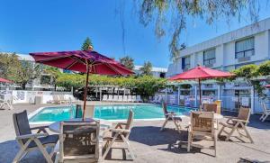 una piscina con mesas, sillas y sombrillas en Motel 6-Belmont, CA - San Francisco - Redwood City, en Belmont