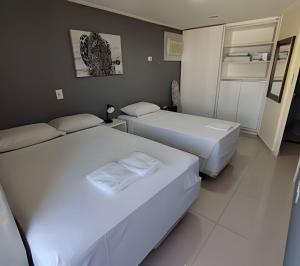 2 Betten in einem Hotelzimmer mit weißer Bettwäsche in der Unterkunft Apartamento Docelar Garagem Feirinha e Hospitais in São Paulo