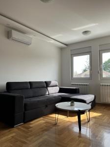- un salon avec un canapé noir et une table dans l'établissement Residence 25V, à Batajnica