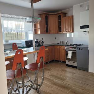 a kitchen with wooden cabinets and orange chairs in it at Apartament Poranek in Grzybowo