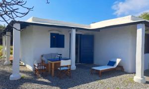 Casa blanca pequeña con mesa y sillas en Lovely independent room in Ecovilla on the beach en Apolakkiá