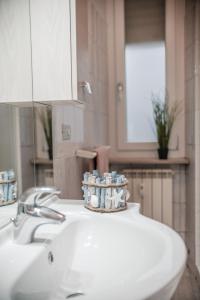 bagno con lavandino bianco e specchio di Appartamento Gufetto a Banchette