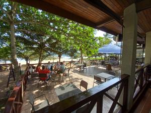 a group of people sitting at tables on a patio at Hotel Palm Rock Beach in San-Pédro