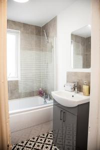 a bathroom with a sink and a tub and a mirror at MantonHouse by Sheryl - Sleeps 7 in Liverpool