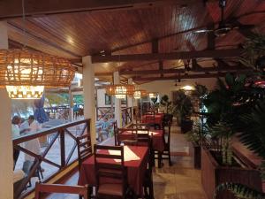 ein Restaurant mit Tischen, Stühlen und Kronleuchtern in der Unterkunft Hotel Palm Rock Beach in San-Pédro