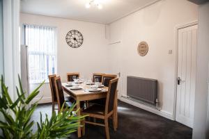 uma sala de jantar com uma mesa com cadeiras e um relógio na parede em MantonHouse by Sheryl - Sleeps 7 em Liverpool