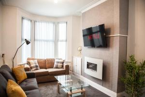 a living room with a couch and a tv on a wall at MantonHouse by Sheryl - Sleeps 7 in Liverpool