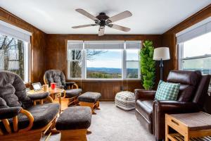 a living room with leather furniture and a ceiling fan at Mountain chalet w hot tub & private balcony in Augusta