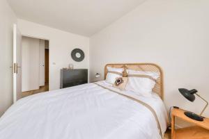 1 dormitorio con 1 cama con colcha blanca en Le Boho Zen - spacieux F3 avec parking proche Paris, en Épinay-sur-Seine