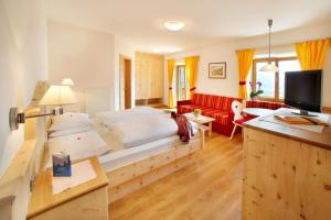 a bedroom with a large bed and a red couch at Garni Sonneck in Laion