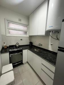 a small kitchen with white cabinets and a stove at Departamento Plaza Colón Yeyita in Mar del Plata
